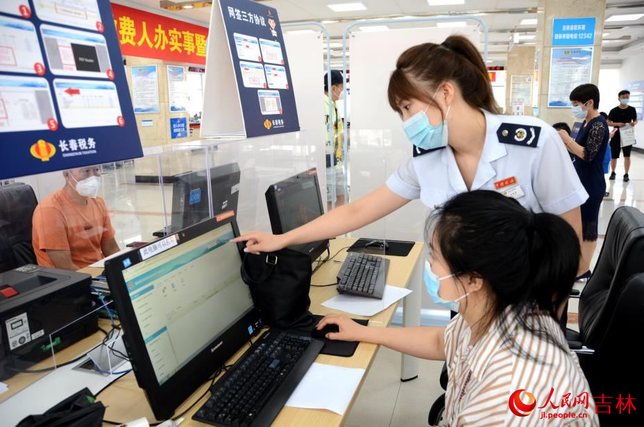 长春市南关区税务局办税大厅内工作人员帮助群众办理业务。人民网 关思聪摄