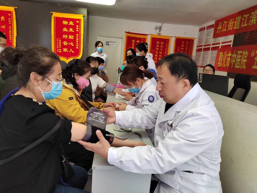 “双报到”中医院党员志愿者免费为居民测量血压、耳穴压豆等检查。