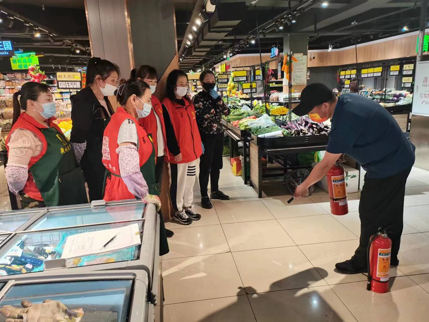 社区网格长进超市讲解灭火器的使用方法。