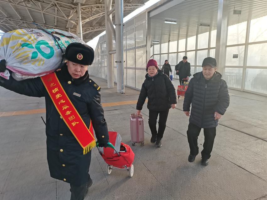 长春车务段公主岭南站爱心服务团队成员帮助旅客搬运大件行李。冯凯摄