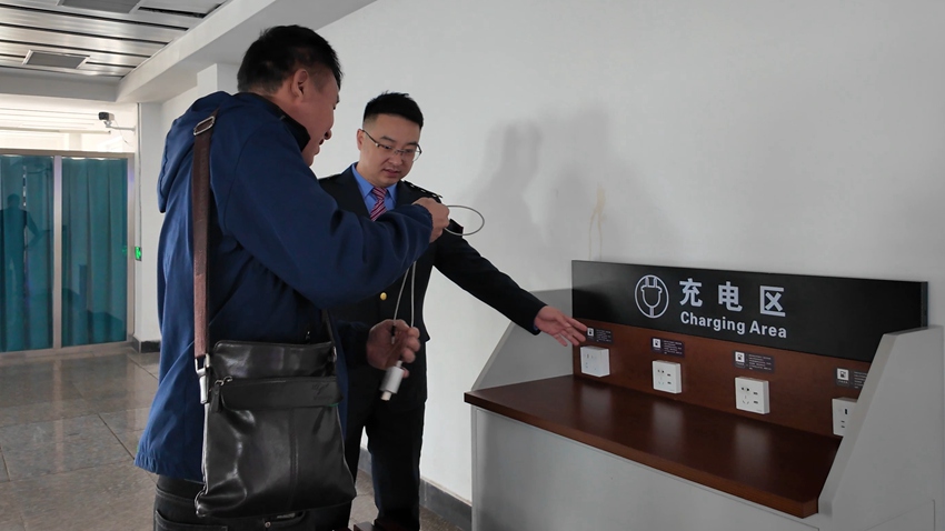 长春车务段公主岭站客运值班员陆程为旅客介绍便民充电区使用。张野摄