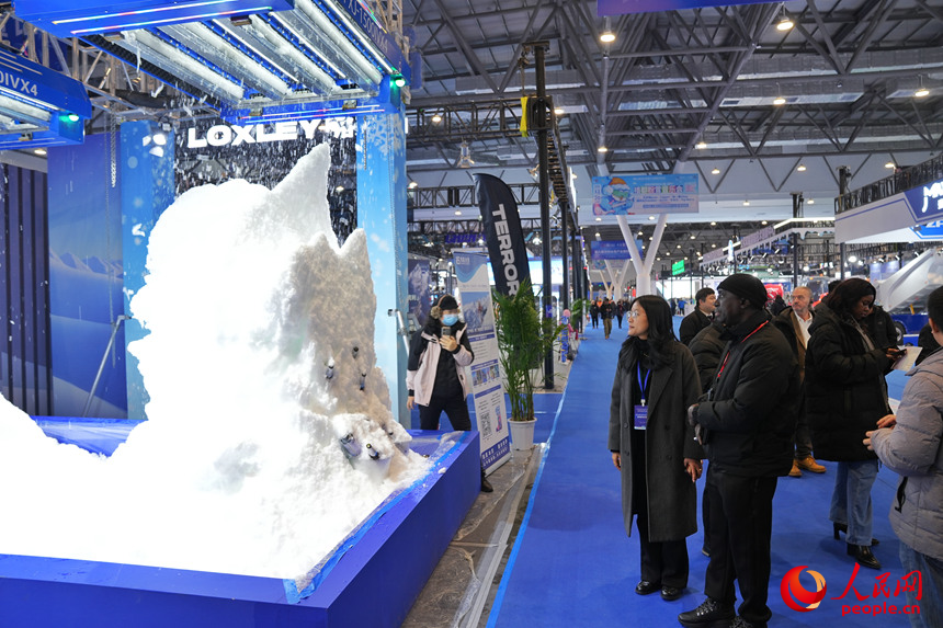 观众在雪博会上观看机器造雪过程。人民网记者 李洋摄