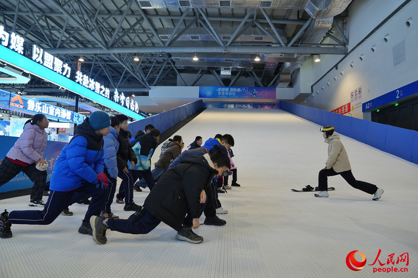 雪博会上，青少年在进行滑雪前的热身运动。人民网记者 李洋摄