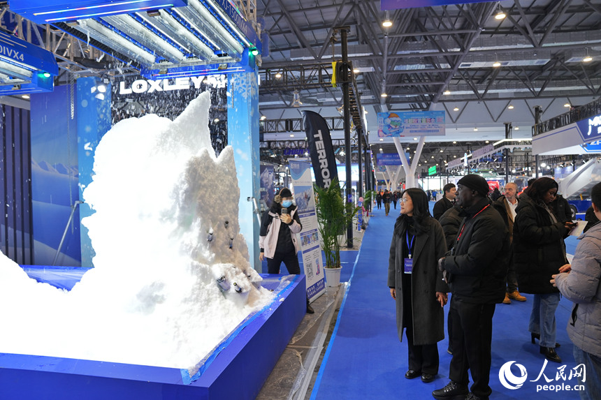 观众在雪博会上观看机器造雪过程。人民网记者 李洋摄