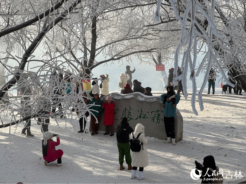 游客们聚集在刻有“雾凇胜景”的字样的石头前合影。人民网记者 李思玥摄