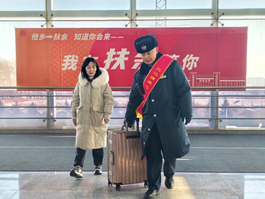 春运首日，沈铁长春车务段扶余北站“三江情”爱心服务团队成员客运员曹东升帮助旅客搬运行李。孙宏宇摄