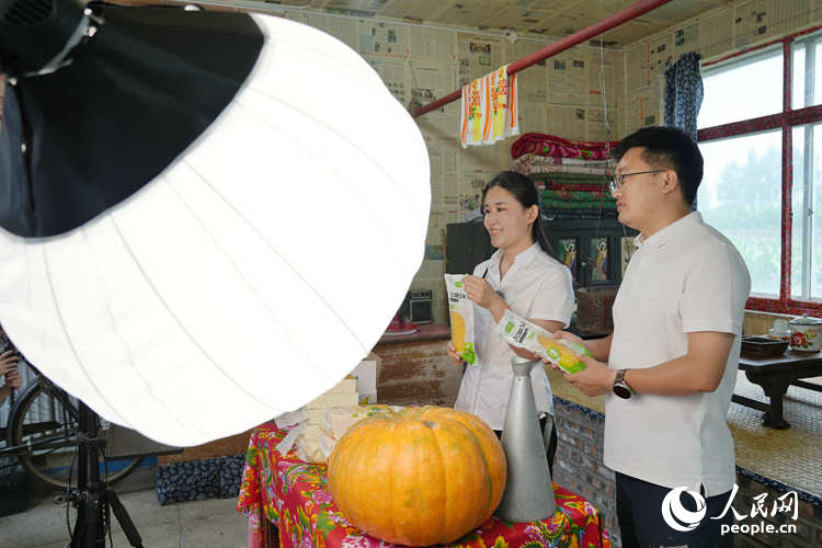 杨荣晶与驻村干部姜昊在村史馆特色农产品直播间带货。人民网记者 李洋摄