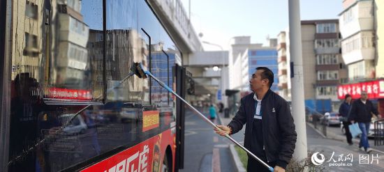 10月4日一早，吉林省长春市271路车站，司机何师傅发车前为公交车做好清洁工作，确保乘客舒心出行。人民网记者 王帝元摄